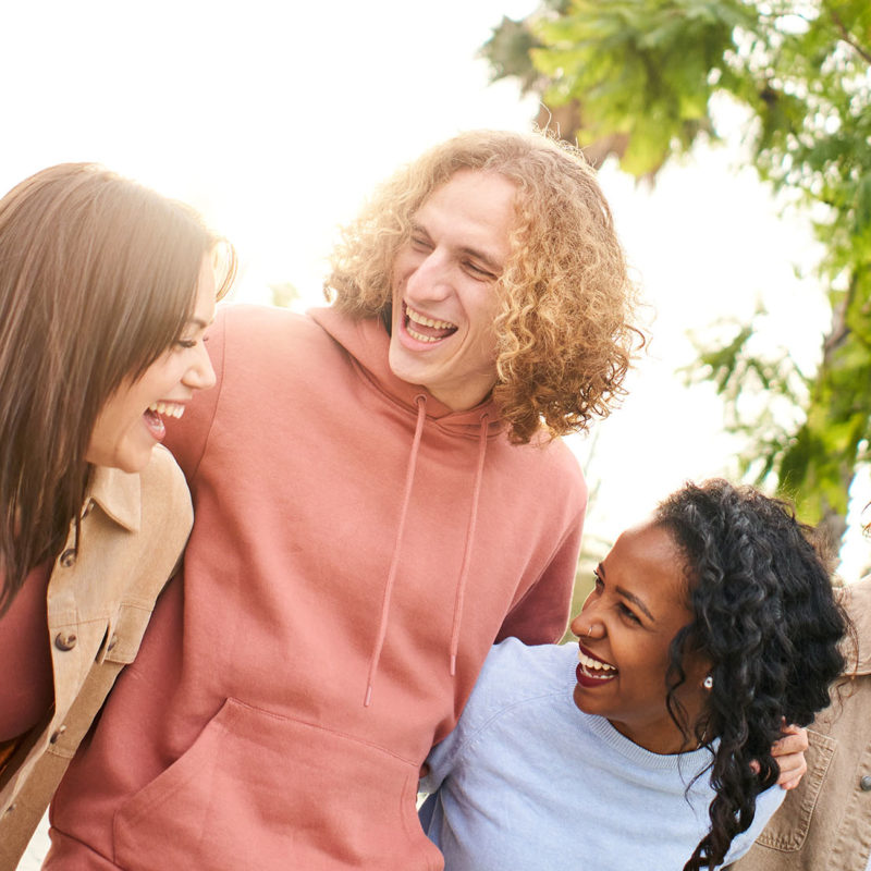 Cheerful group of friends walking and laughs outdoors in the park. Young happy people having fun. High quality photo