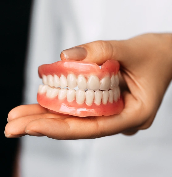 Hand holding a full set of removable dentures