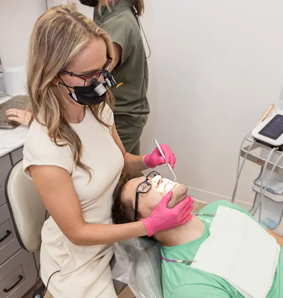 Dentist in pink gloves performing gum disease treatment on patient in dental office.