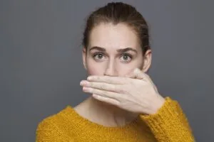 Woman covering her mouth because of bad breath concerns